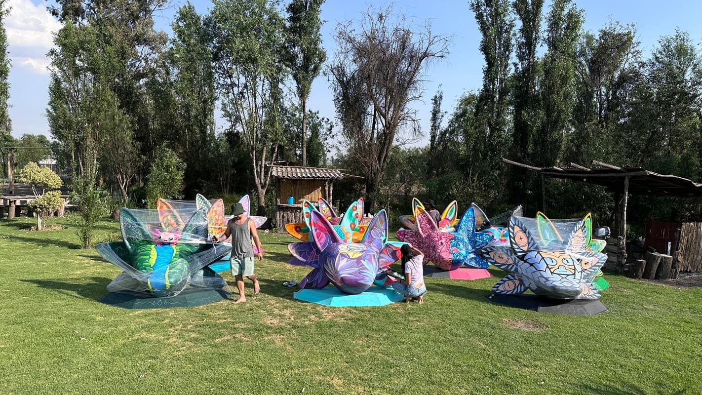 Painted axolotl sculptures spread across the lawn with visitors among them