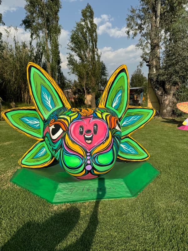 A leafy green sculpture with a red face