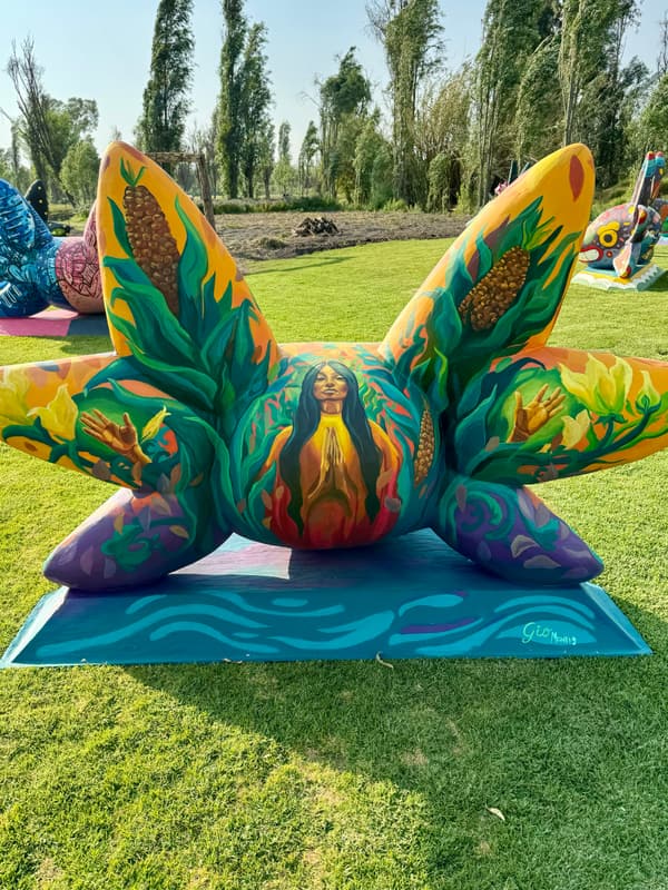 A teal and orange sculpture painted with foliage