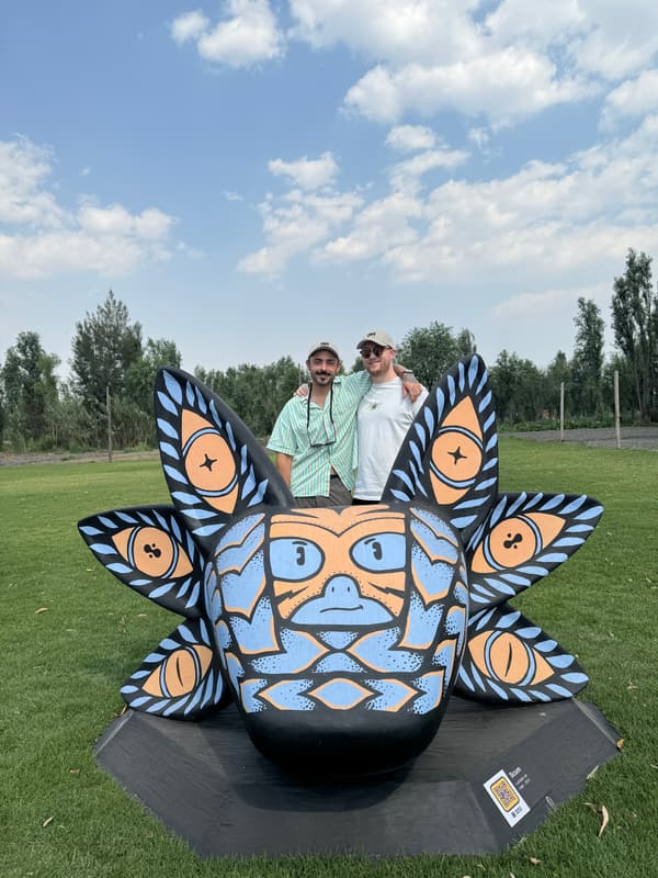Two visitors posing behind a blue and white sculpture