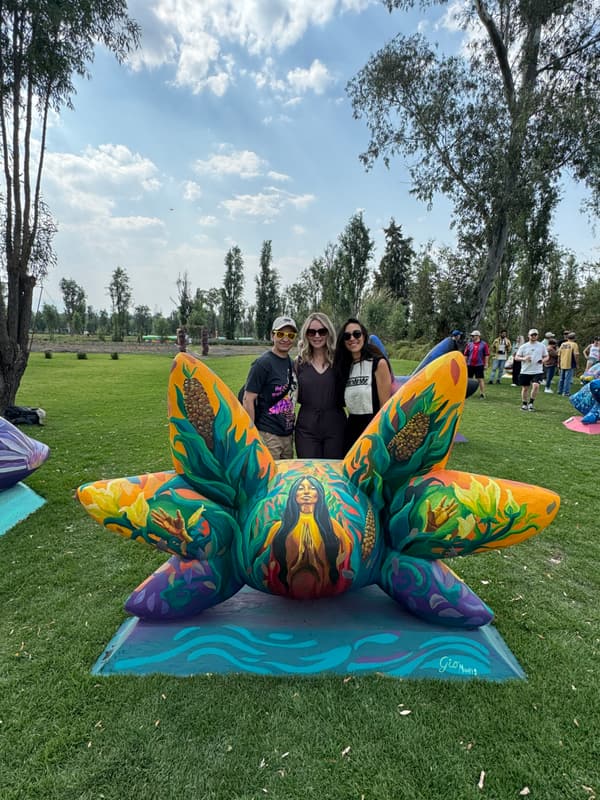 Three visitors behind a teal and orange sculpture