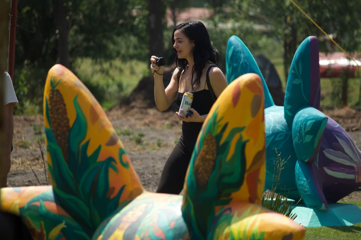 A visitor filming beside a green and orange sculpture