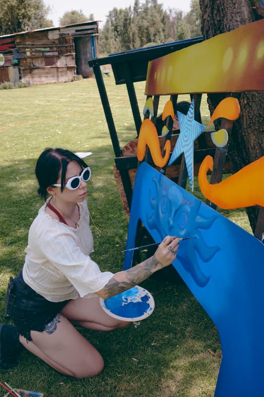 An artist painting a blue axolotl sculpture on the grass