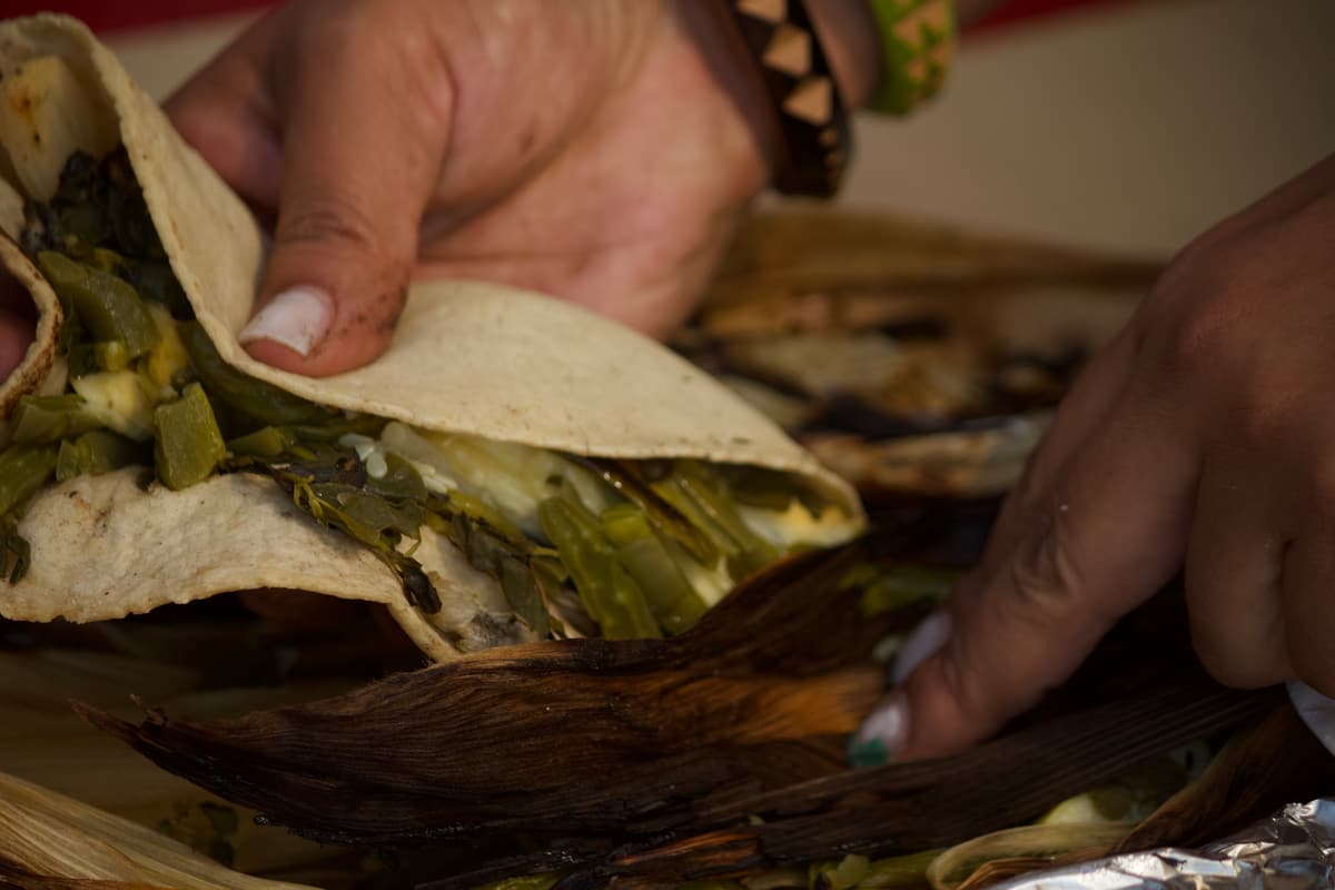 Hands opening a freshly steamed tamal