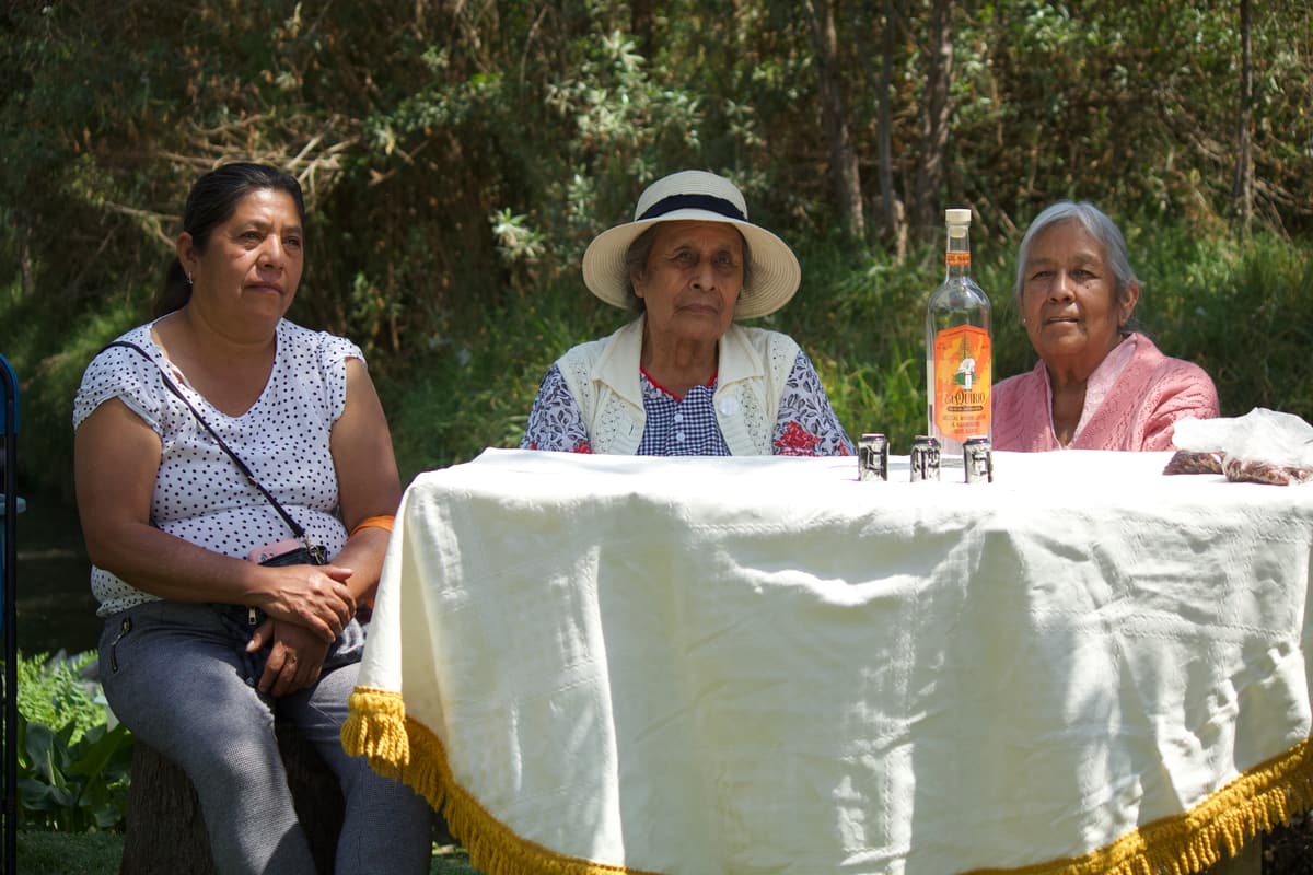 Three women seated at a table on the chinampa