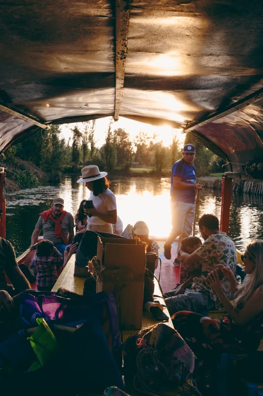Guests aboard a trajinera as the sun sets over the canal