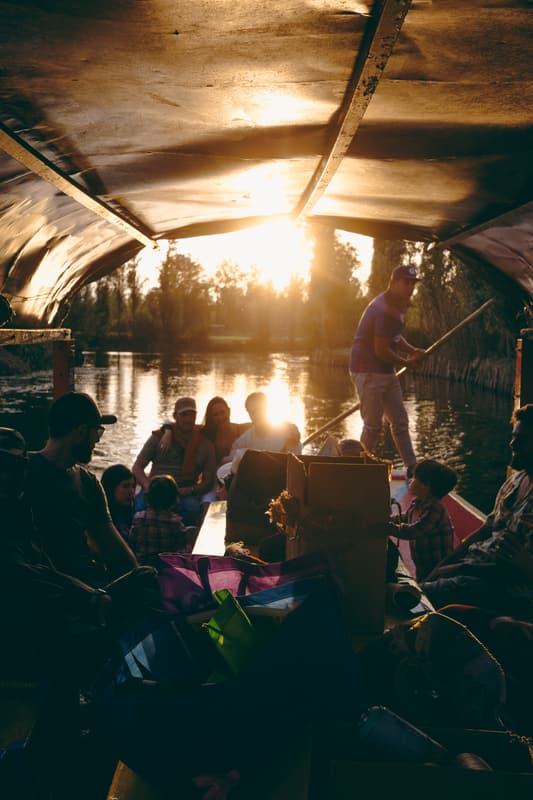 A boatman poling a trajinera through golden-hour light