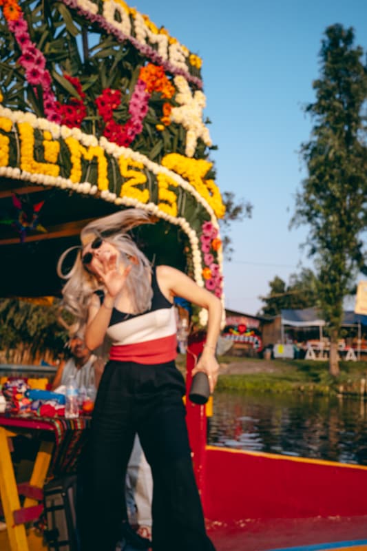 A guest dancing on a flower-covered trajinera