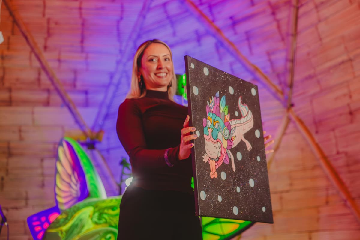 An artist presenting her painted canvas