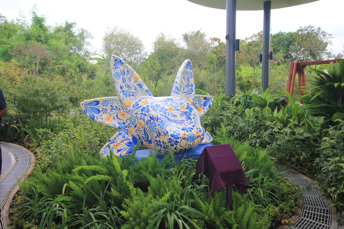 The talavera-patterned axolotl sculpture among ferns at Gardens by the Bay