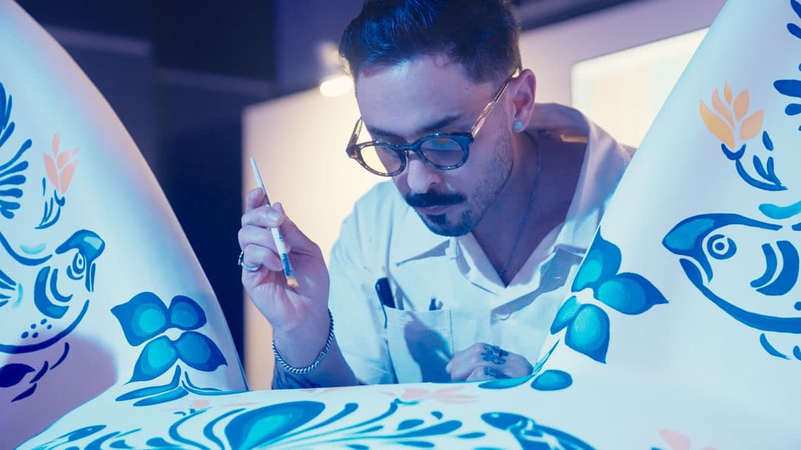 An artist working on the blue-and-white painted axolotl sculpture