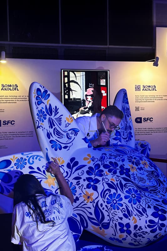 An artist leaning over the sculpture to paint its back