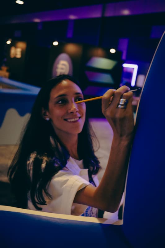 An artist smiling with a brush in hand beside the sculpture