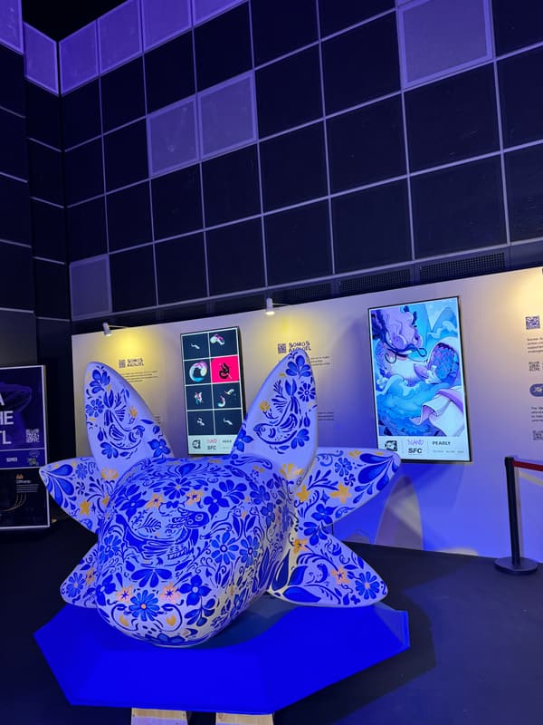 The finished sculpture lit blue in front of the display screens